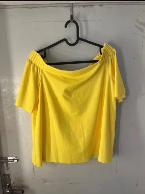Gul offshoulder topp  - Snygg gul offshoulder topp med korta ärmar och elastisk kant. Perfekt för dig som vill ha en färgstark och luftig stil. Materialet är mjukt bomull som känns skönt mot huden och toppen har en enkel, stilren design. Sååå himla snygg till sommaren när man är tan!