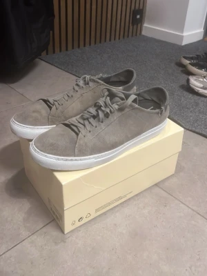 Grå mockasneakers från Axel Arigato - Säljer ett par snygga mocka skor från arigato i storlek 42. Det finns lite små defekter på skorna som sänker värdet på dom, så detta är en anledning till varför priset är så lågt, deffekterna på skorna är där bak vid skorna som ni ser på bilden, inget man lägger märke till, annars så är skorna mycket bra 