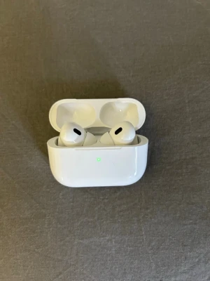Apple AirPods Pro kopia - Säljer ett par Apple AirPods Pro med vitt laddningsetui. Hörlurarna är trådlösa och har en kompakt, stilren design med silikonproppar och touchkontroll. Perfekt för musik, samtal och gaming. Laddningsetuiet har LED-indikator på framsidan. Inte Apple 