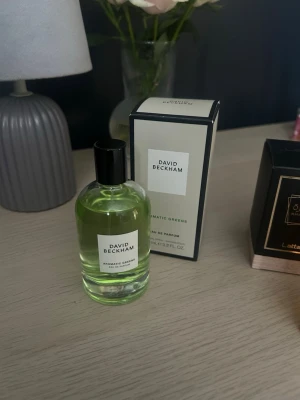 David Beckham Aromatic Greens parfym - Fräsch Eau de Parfum från David Beckham med grön, transparent vätska i en rund glasflaska med svart kork. Kommer med matchande kartong i ljusgrönt och svart. Perfekt för dig som gillar moderna och stilrena dofter.