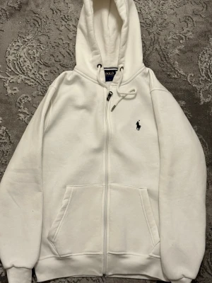 Vit hoodie från Polo Ralph Lauren - Fin stilren klassisk Ralph Lauren hoodie med dragkedja framtill och broderad logga på bröstet passar alla tillfällen som ny använd fåtal gånger, pris kan diskuteras vid snabb affär.