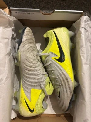 Nike fotbollsskor gul/grå med dobbar - Säljer ett par Nike fotbollsskor i grått och neongult med svarta detaljer. Det är elite inte änvänt så mycket äkta har väska också 