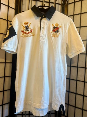 Ralph Lauren polo tröja crest patch 💥 - Snygg vit polo från Polo Ralph Lauren med feta broderade logos + stor “3” patch på ärmen 🔥  Ger clean rich/old money vibe men ändå street med oversized fit. Perfekt till baggy jeans / kjol / sneakers.  Storlek: M (kan fit L lite loose) Skick: Bra skick  ⸻  📦 Skickas snabbt