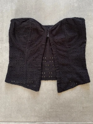 Svart korsettopp - Snygg svart korsettopp med broderade detaljer och hålmönster från HM. Den är knappt använd och i storlek s.❤️