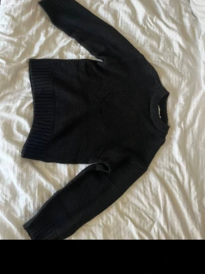 Svart stickad tröja från NA-KD - En svart stickad tröja från NA-KD i storlek XS. Tröjan har rund halsringning, långa ärmar och ribbade muddar vid ärmslut och nederkant. Perfekt för lager på lager och enkel att matcha med olika outfits.
