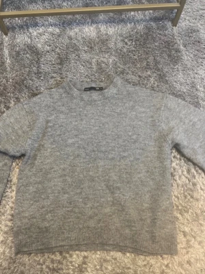 Grå stickad tröja från Gina Tricot - Mysig grå stickad tröja från lager 157 med rund halsringning och ribbade muddar vid ärmslut och nederkant. Perfekt för lager på lager och enkel att matcha med jeans eller kjol. Klassisk och stilren modell i mjukt material. Pris kan diskuteras 