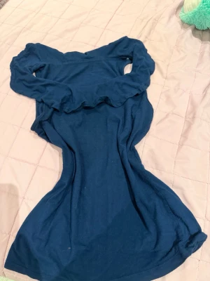 Marinblå offshoulder klänning - Snygg marinblå klänning med offshoulder-design och volangdetalj upptill. Klänningen har en kroppsnära passform och är tillverkad i ett mjukt tyg som ger en bekväm känsla. Perfekt för dig som vill ha en enkel men trendig look.