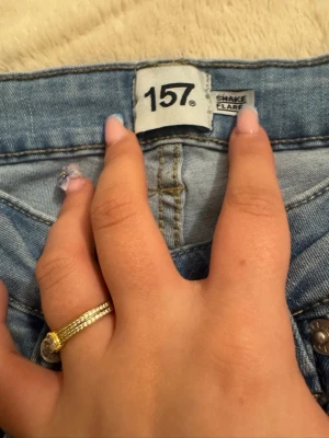 Ljusblåa flare jeans från 157 - Säljer ett par ljusblåa snake flare jeans från 157. Jeansen har hög midja och riktigt utsvängda ben, perfekt för dig som gillar retrostil. Klassisk femficksmodell och tillverkade i mjukt denimtyg. Snygga att styla med sneakers eller boots.