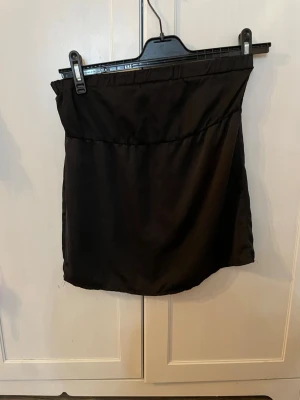 Svart axelbandslös tubtopp - Snygg svart tubtopp i slätt material med enkel och stilren design. Pris kan diskuteras. Köparen står för frakt.