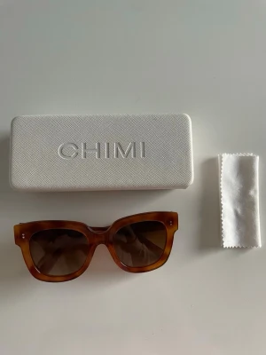 Bruna solglasögon från CHIMI - Snygga solglasögon från CHIMI, modell 08 med fyrkantig form och bruna bågar i transparent acetat. Kommer med vit hård förvaringsbox och putsduk. Perfekta för soliga dagar och ger en cool vibe till din outfit. Skäöldpadds färg