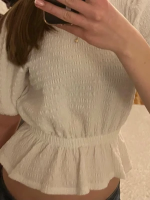 Vit blus med volangdetalj - Säljer en vit blus med smockad struktur och volang nedtill💗