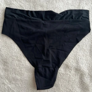 Svarta trosor med bred linning - Säljer ett par svarta trosor med bred, mjuk linning och hög midja. Trosorna har en enkel och stilren design i stretchigt material som känns bekvämt mot huden. Perfekta för dig som gillar klassiska underkläder med modern twist. Ny pris 150kr