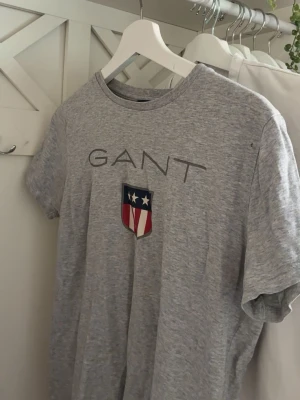 Grå GANT t-shirt med logga - Snygg grå t-shirt från GANT. använd ett par gånger lite sliten, 👕