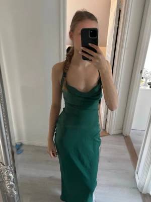 Grön balklänning - Snygg grön balklänning med smala axelband och figurnära passform. Klänningen har en djup urringning och är ärmlös. Pris går att diskutera vid snabb affär