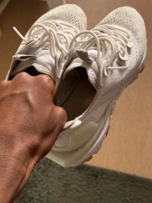 Vita sneakers med meshdetaljer - Snygga vita sneakers med ventilerande meshdetaljer och klassisk snörning. Skorna har en chunky sula och sportig look som passar perfekt till streetwear. Materialet är en mix av textil och syntet för extra komfort.