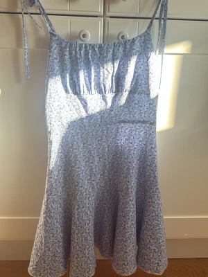 Ljusblå blommig sommarklänning - Söt ljusblå klänning med små tunna axelband som knyts. Använt fåtal gånger. Lämna prisförslag💕