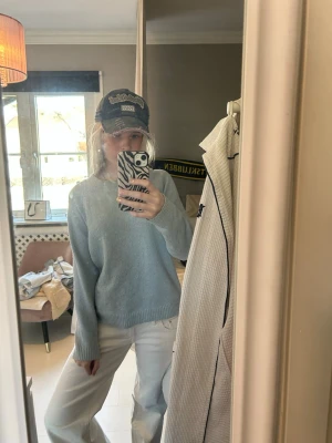 Ljusblå stickad tröja - Mysig ljusblå stickad tröja med rund halsringning och ribbade muddar vid ärmslut och nederkant. Tröjan har en avslappnad passform och är perfekt för lager på lager. Materialet ser ut att vara mjukt och bekvämt, troligen bomull eller ullblandning.