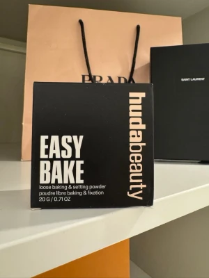 Huda Beauty Easy Bake Banana Bread - Lös baking & setting powder från Huda Beauty i nyansen Banana Bread. Kommer i en svart fyrkantig förpackning med beige text. Perfekt för att fixera foundation och ge en matt finish. Innehåller 20 g puder HELT NY.
