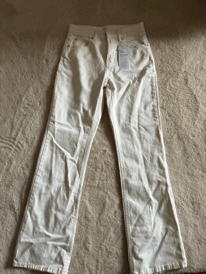 Vita jeans från Gina Tricot - Säljer ett par vita bootcut jeans från Gina Tricot i modellen Classic Boot. Jeansen har hög midja, raka ben och klassisk femficksdesign. Helt oanvända💓