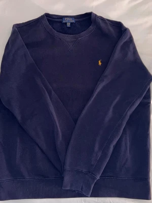 Blå Ralph Lauren Tröja - Säljer denna blå tröjan från Ralph lauren. Tröjan är i mycket fint skick då den inte använts mycket. Den ser lite smutsig eller röd ut på bilderna p.g.a ljuset, men har inga fläckar eller liknande. Den har storlek XL, men sitter ungefär som M. Tveka inte att höra av dig vid frågor. Priset är diskuterbart.