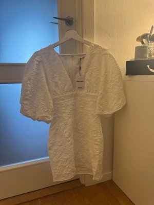 Showpo klänning - Superfin klänning i strukturerat tyg med V-ringning, markerad midja och puffärmar. Figurnära modell med dragkedja bak. Storlek 6 (xs)  Perfekt till fest, student eller sommar 🌸  Skick: ny med lappar kvar  Säljer då jag har hittat en annan klänning jag vill ha.  Ge gärna prisförslag! 