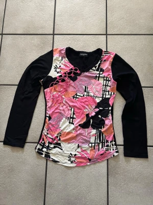 Sophytine Paris Blommig långärmad topp i rosa och svart storlek S/M - Snygg långärmad topp  med svart ärm och färgglad framsida i rosa, svart, orange och vitt. Blommigt mönster och v-ringad hals. Perfekt för dig som gillar färg och vill sticka ut lite extra.