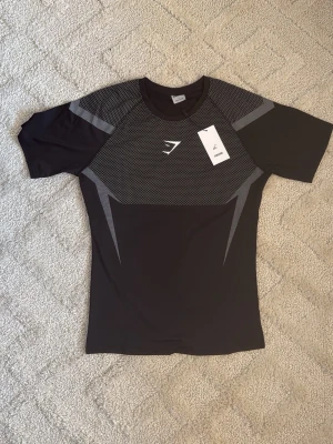 Gymshark Onyx V5 Tröja – Svart & Vit - Gymshark Onyx V5 Tröja – Svart & Vit 👕 Storlek: L ⚫⚪ Färg: Svart med vita detaljer ✨ Skick: Nyskick – endast testad 🧵 Modell: Onyx V5