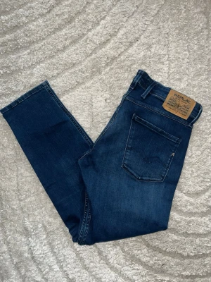 Replay Anbass Jeans - Mörkblåa replay Anbass jeans med slimfit. Midja 42cm, längd 95cm. Obs L storleken saknas men jag skulle bedöma till L30 - men utgå efter mått. JAG SKICKAR EJ FLER BILDER NÄR JAG BÄR JEANSEN! för bättre inblick i passformen rekommenderar jag att googla på modellnamnet. För storleksguide kolla måtten noggrant då jeansen alltid kan vara uppsydda heller krympta och jag ej tar emot returer :) 1,93