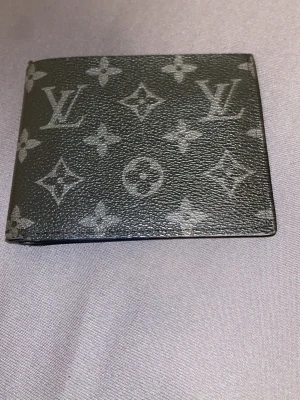 Zara  monogram plånbok - Snygg svart plånbok från Zara  med klassiskt monogrammönster i grått. Tillverkad i äkta läder och har flera kortfack på insidan. Perfekt för dig som vill ha en stilren och lyxig accessoar från ett ikoniskt märke.