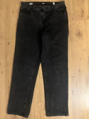 Svarta loose chris jeans Jack & Jones - Säljer ett par svarta loose chris jeans från Jack & Jones i storlek 170. Klassisk femficksmodell med dragkedja och knapp i midjan. Jeansen har raka ben och är tillverkade i slitstarkt denimtyg. Perfekta för en avslappnad och trendig look.
