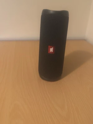 JBL Flip bärbar högtalare svart - Snygg och kompakt JBL Flip bärbar högtalare i svart med robust tygmaterial och gummerade kanter. Cylindrisk form med tydliga volymknappar och praktisk bärrem. Perfekt för att ta med sig musiken överallt. Prissättning kan diskuteras 