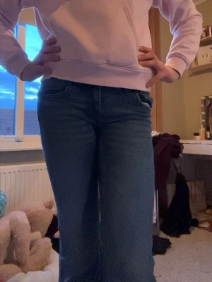 Blå bootcut jeans med paljettdetalj på fickan - Säljer ett par blå bootcut jeans med snygg paljettdetalj på bakfickan. Jeansen har klassisk femficksmodell och normal midja. 