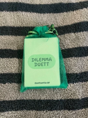 Dilemma Duett kortspel - Dilemma Duett är ett kortspel på svenska där spelare argumenterar kring olika dilemman. Korten är ljusgröna och spelet levereras i en grön tygpåse. Perfekt för dig som gillar diskussioner och vill utmana dina vänner i vem som har bäst argument! 😝OBS färgen i de första bilderna ser annorlunda ut pgr av ljuset 🤗