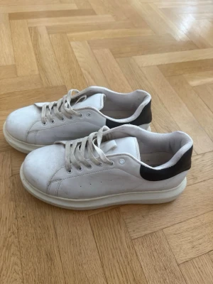 Vita chunky sneakers med svart detalj - Snygga vita sneakers med svart detalj baktill. Storlek 39. Använda men i bra skick. Viss smuts och mindre märken finns (se bilder). 
