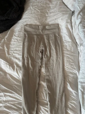 Beige ribbade seamless tights - Säljer ett par beige ribbade tights från Gavelo med hög midja och seamless design. De är stretchiga och har en bred linning för extra komfort. Perfekta för en avslappnad och trendig look.