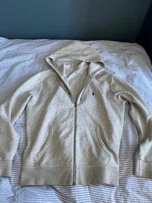 Polo Ralph Lauren zip hoodie strl M - Säljer en zip hoodie ifrån Polo Ralph Lauren i strl M. Den är i melerad ljusgrå och i mycket bra skick. Nypris ~ 2000 kr. Hör av er vid frågor och funderingar!
