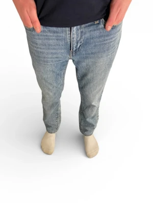 Levi's 501 ljusblå straight jeans - Klassiska Levi's 501 jeans i ljusblå tvätt med rak passform och normal midja. Jeansen har fem fickor, knappgylf och den ikoniska läderpatchen bak i midjan. Tillverkade i slitstark bomull, perfekta för en avslappnad och tidlös stil. nästan aldrig använda!! Hör av er via funderingar!!