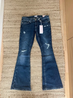 Blå lågmidjade bootcut jeans från Gina 14+ - Säljer ett par blå lågmidjade bootcut jeans från Gina Tricot 14+ som är väldigt populära. Dom är helt nya med alla lappar kvar osv. Dessa kommer till säljning då dom tyvärr är försmå, så är öppen att byta med L om någon är intresserad. Ordrenarie pris är 359kr (kan tyvärr it skicka bild hur dom sitter på pga att dom just är försmå)