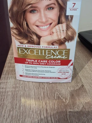 Excellence Creme hårfärg 7 Blonde - Excellence Creme hårfärg i nyansen 7 Blonde. Färgen är blond och kommer i en förpackning med skyddande färgkräm, vårdande efter-färg shampoo och närande hårmask. Berikad med hyaluronsyra för extra vård och glans. Ger upp till 100% grå täckning.
