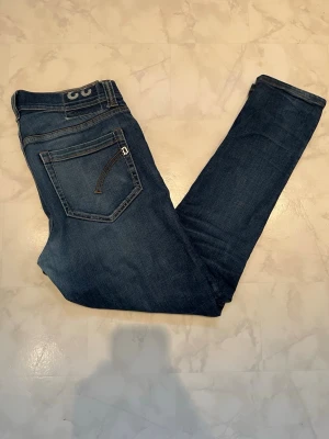 Dondup Jeans - Snygga mörkblå slim fit jeans med klassisk femficksdesign och kontrastsömmar. Jeansen har en rak passform och är tillverkade i mjukt denimtyg som ger en bekväm känsla. Perfekta för en avslappnad och trendig stil.