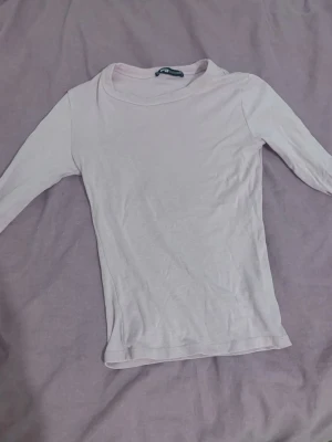 Ljusrosa långärmad topp från Gina Tricot - En enkel och stilren ljusrosa långärmad topp från Gina Tricot. Toppen har en rund halsringning och är gjord i mjuk bomull, perfekt för att matcha med jeans eller kjol. Passformen är slim och materialet känns skönt mot huden.