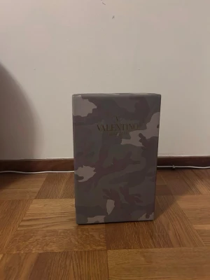 Valentino rockrunners - Säljer ett par Valentino rockrunners storlek 45  får med dustbag i rött tyg med svart logga samt originalkartong i grått kamouflagemönster. Perfekt för att förvara eller skydda dina skor eller  från Valentino. Dustbagen är mjuk och boxen är i hård kartong.