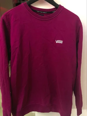 Vinröd sweatshirt från Vans - Säljer en vinröd sweatshirt från Vans med broderad logga på bröstet. Tröjan har rund halsringning, långa ärmar och är gjord i mjuk bomullsmix. Perfekt för en avslappnad och stilren look.
