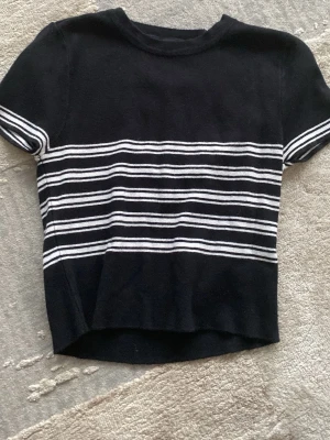 Svart och vit randig topp från TW - Svart kortärmad topp från TW med vita horisontella ränder över bröstet och ärmarna. T-shirten har en klassisk rund halsringning och en slim passform. Perfekt för en stilren och enkel look. Använd typ 5-6 gånger 💕🫰🏼