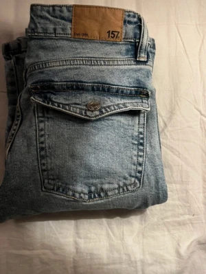 Ljusblå raka jeans från 157 - Säljer ett par ljusblå jeans från 157 med klassisk femficksmodell och raka ben. Jeansen har en snygg vintage tvätt och detaljer i silverfärgad metall. Perfekta för en avslappnad och trendig stil. Jeansen finns på flera sidor🩷