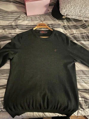 Mörkgrön stickad tröja från Morris - Snygg mörkgrön stickad tröja från Morris med rund halsringning och diskret logga broderad på bröstet.. Perfekt för lager på lager och stilrena outfits.