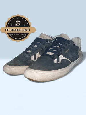 Mörkblå sneakers från Pepe Jeans - Snygga mörkblå sneakers från Pepe Jeans med vita detaljer och logga på sidan. Skorna har lågt skaft, vita sulor och ovandel i mocka och textil. Perfekta för en avslappnad streetstyle-look.