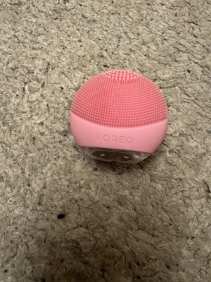 FOREO ansiktsrengöringsborste rosa - Smidig ansiktsrengöringsborste från FOREO i en söt rosa färg. Tillverkad i mjukt silikon med små borst för skonsam rengöring av huden. Rundad form som ligger bra i handen och laddningsbar via port på baksidan.