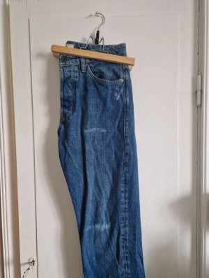 Blå raka jeans med sliten look. - Säljer ett par klassiska blå jeans med rak passform och hög midja. Herr st 28, 30 