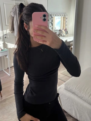 Mörkgrå långärmad fleece-tröja - Säljer en mörkgrå långärmad tröja med fleece på insidan. Tröjan är figurnära och har en enkel, stilren design utan mönster eller logga. Perfekt för dig som gillar att hålla dig varm och samtidigt se snygg ut.